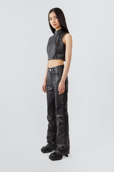 Side view of a model wearing the Sporty Top, a cropped leather vest with a sleek central zipper and short standing collar, crafted from upcycled lambskin leather.