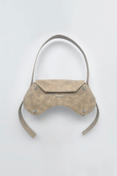 The Stella Bag in beige is crafted from upcycled leather with silver details and lined with cotton. It features an adjustable shoulder strap and has measurements of 14 cm height, 30 cm width, and 6.5 cm depth.