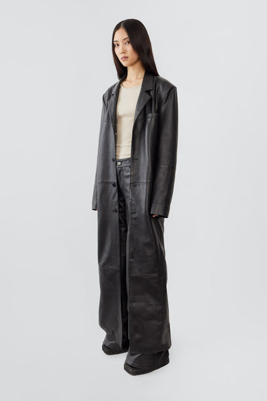 Side view of Vargen leather coat by Deadwood, showcasing ultra-long length and relaxed oversized fit, made from upcycled lambskin.
